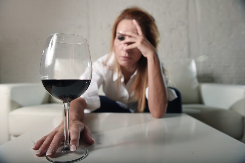 alcohol rehab in Kansas, alcohol rehabilitation, alcohol addiction, upset woman reaching for wine glass - alcohol