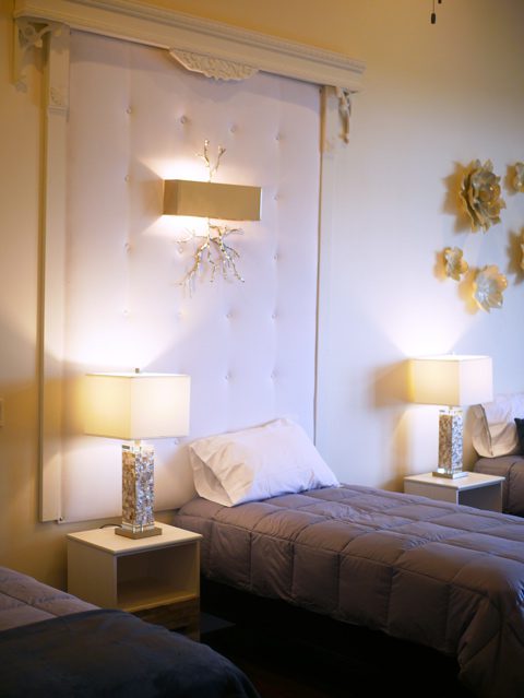 beautiful cream colored bedroom with 3 beds and lamps with square ivory shades