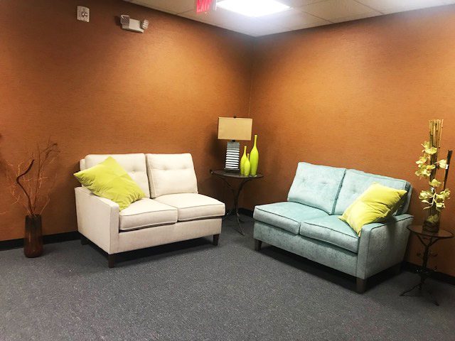 tan room with grey carpet and 2 love seats with yellow pillows