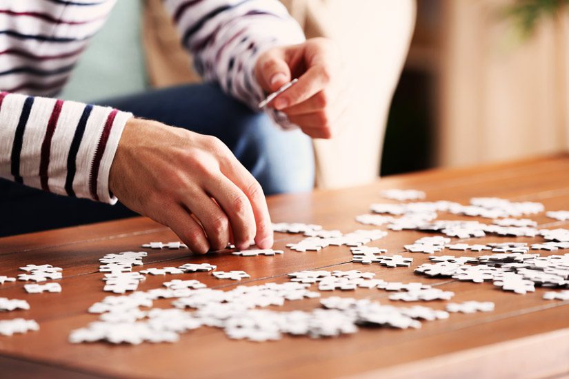 closeup of young man doing a jigsaw puzzle - hobbies