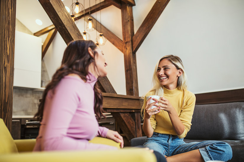 two pretty young women talking happily over coffee - recovery mentor