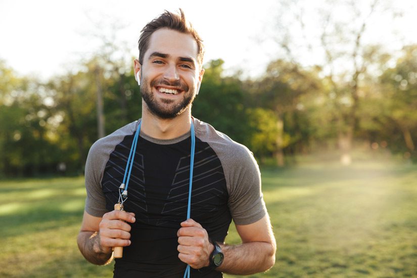 smiling young man at park with jump rope around his neck - lifestyle changes