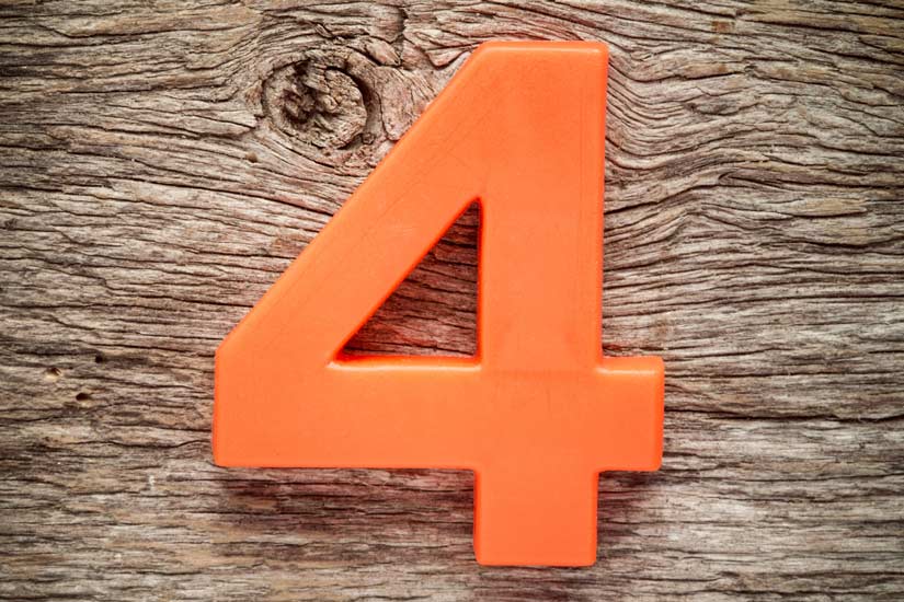 closeup of large plastic looking bright orange number four on an unfinished wooden table - emotions